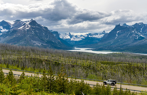 A stormy Spring evening view of Highway 89 running at side of Saint Mary Lake and its surrounding steep high peaks. Glacier National Park. Montana, USA.