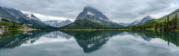 A panoramic view of Swiftcurrent Lake, with Mt. Grinnell towering at west shore and Mt. Wilbur and Mt. Gould disappeared in thick clouds, on a stormy Spring evening. Many Glacier, Glacier National Park. Montana, USA. spring mountain lake - una vista tormentosa de la noche de primavera del lago swiftcurrent, con el monte grinnell elevándose en la costa oeste y el monte wilbur y el monte gould desaparecieron en espesas nubes, el parque nacional glacier.