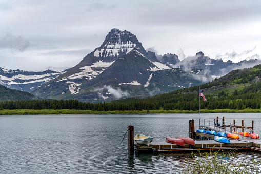 Lanzamiento de bote en el lago Swiftcurrent - Una bandera de los Estados Unidos ondeando sobre un bote de lanzamiento en el lago Swiftcurrent, con el Monte Wilbur elevándose en la costa oeste, en una tormentosa mañana de primavera, parque nacional Glacie photo