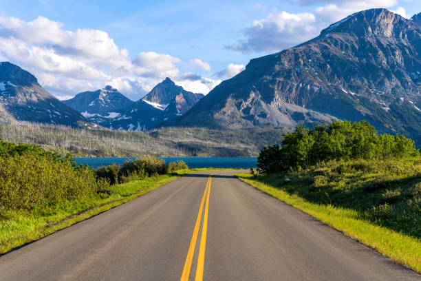 go to the sun road - a spring evening view of an east section of go to the sun road at saint mary lake, with rugged high peaks towering in the background. glacier national park. - dusk blue montana landscape imagens e fotografias de stock