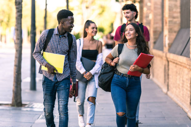 istock Four students of different ethnicities walking in outdoors with school material 1347549391