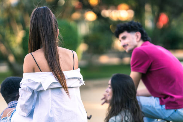 istock Back of multiethnic people talking while sitting on a bench in a park 1347550997