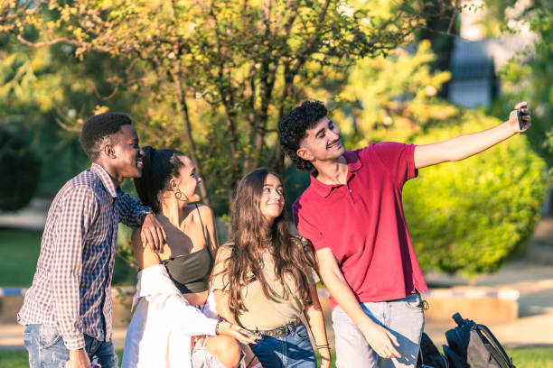 istock Group of multiethnic young people taking a selfie with a mobile in a park 1347552192