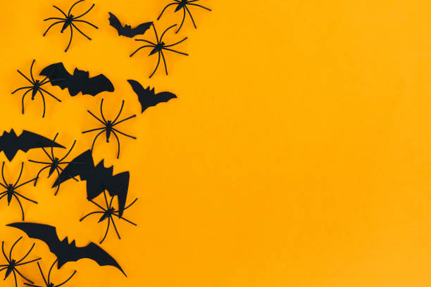 istock Happy Halloween. Spiders and bats flat lay on orange background with space for text. Season's greeting card. Halloween decorations border on yellow paper. Minimalist 1347552579