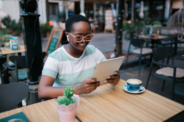 istock Happy African American woman using a digital tablet computer in a coffee shop 1347553329
