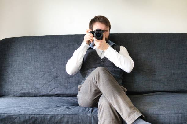 istock Bearded photographer sitting on a couch wearing a grey vest. 1347554692