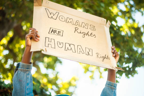 Young woman holding up a women's rights protest sign outside stock photo