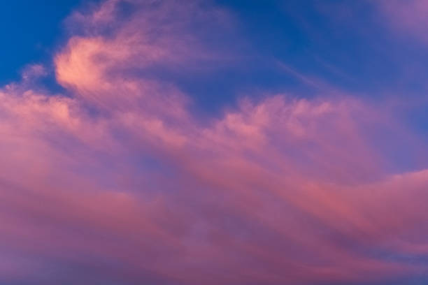 istock Clouds in the blue sky in the rays of the summer setting sun. 1347558782