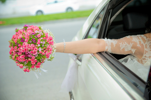 The bride took out the flower bouquet out of the car