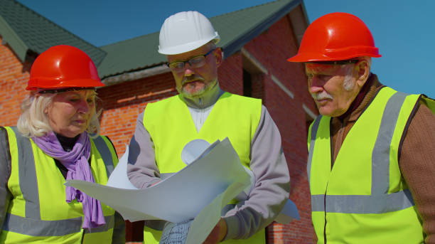 istock Architect with senior civil engineers discussing project work with blueprint of building new house 1347564782
