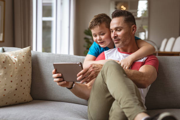 istock Caucasian father and son using digital tablet on the couch at home 1347569752