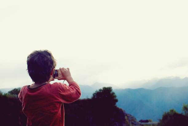istock Child Photographing Cloudy Mountainscape 1347572639