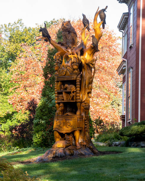 Bangor, ME - USA - Oct. 12, 2021: View of Josh Landry's dead ash tree sculpture of a towering wooden bookcase mounted on human legs that features several birds, a cat, and a likeness of a beloved dog.