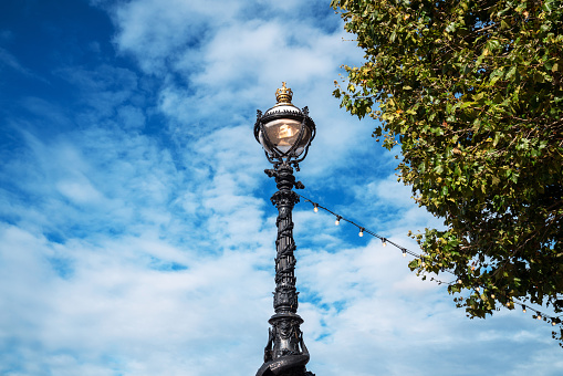 Wrought iron street light with artistic forging beautiful decorative vintage against the gray sky.