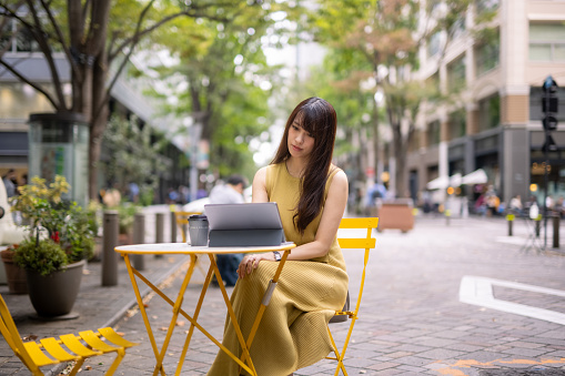 Japanese woman in yellow dress visiting Marunouchi, Tokyo on weekend to enjoy tea time and shopping.