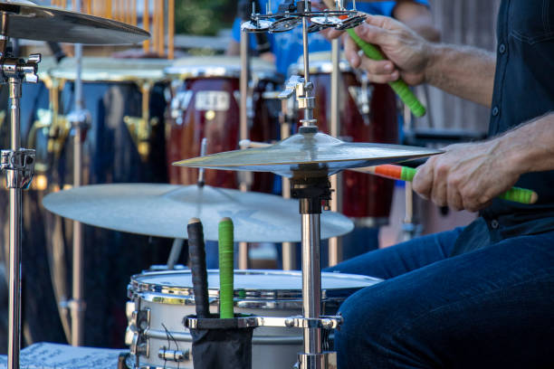 istock Side view close-up of dummer playing drum kit outdoors, cropped to torso and hands, with multiple cymbals and snare 1347576417
