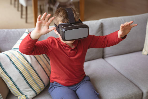 istock Caucasian boy wearing vr headset gesturing while sitting on the couch at home 1347577252
