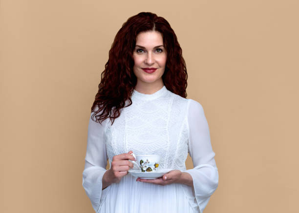 istock Woman with Soft Smile Holds Teacup Isolated Against Beige Background 1347580452