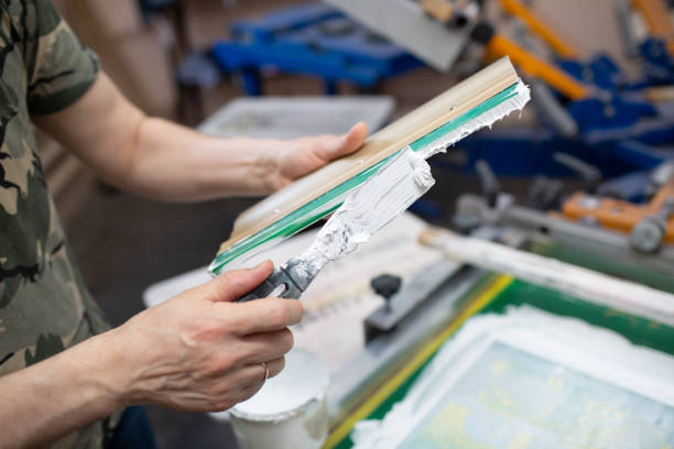 istock Serigraphy silk screen print process at clothes factory. Cleansing Frame, squeegee and plastisol color paints 1347581461