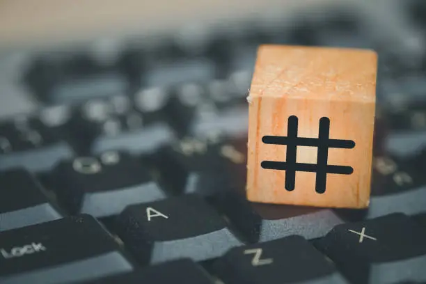 Photo of Hashtag symbol on wooden cube put on black computer keyboard. Close up