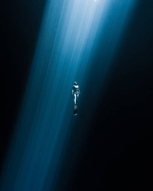 Japanese freediver swimming to the surface in a  Mexican Cenote A freediver surfaces through the unique light in a  freshwater Cenote, this places have been special sanctuaries for Ancient cultures in Mexican territory snorkeling photos stock pictures, royalty-free photos & images