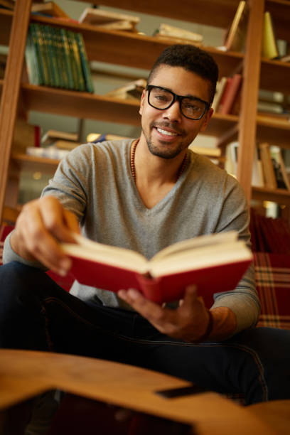 istock Smiling African American student enjoying book reading in library 1347594002