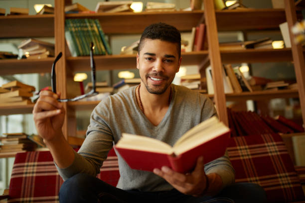 istock Smiling African American student enjoying book reading in library 1347594044