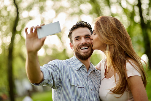 Young affectionate couple taking Selfie in the public park