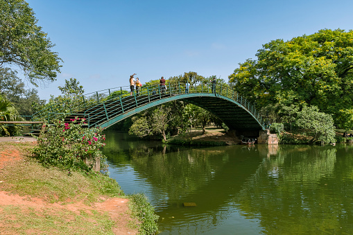 São Paulo - Brazil - September 30, 2021: Ibirapuera Park. Bridge over the lake with people enjoying the view on a sunny afternoon with blue sky.