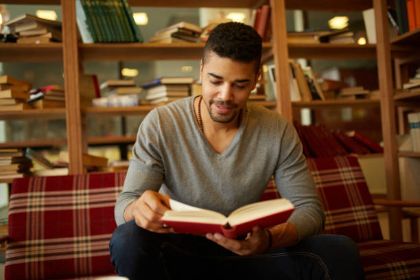 istock Smiling African American student enjoying book reading in library 1347595033