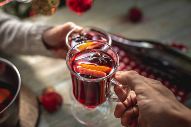 Man and a woman is drinking fragrant hot mulled wine in a cozy home festive atmosphere. Concept of New Year and Christmas mood. Closeup Man and a woman is drinking fragrant hot mulled wine in a cozy home festive atmosphere. Concept of New Year and Christmas mood. Closeup. mulled wine stock pictures, royalty-free photos & images