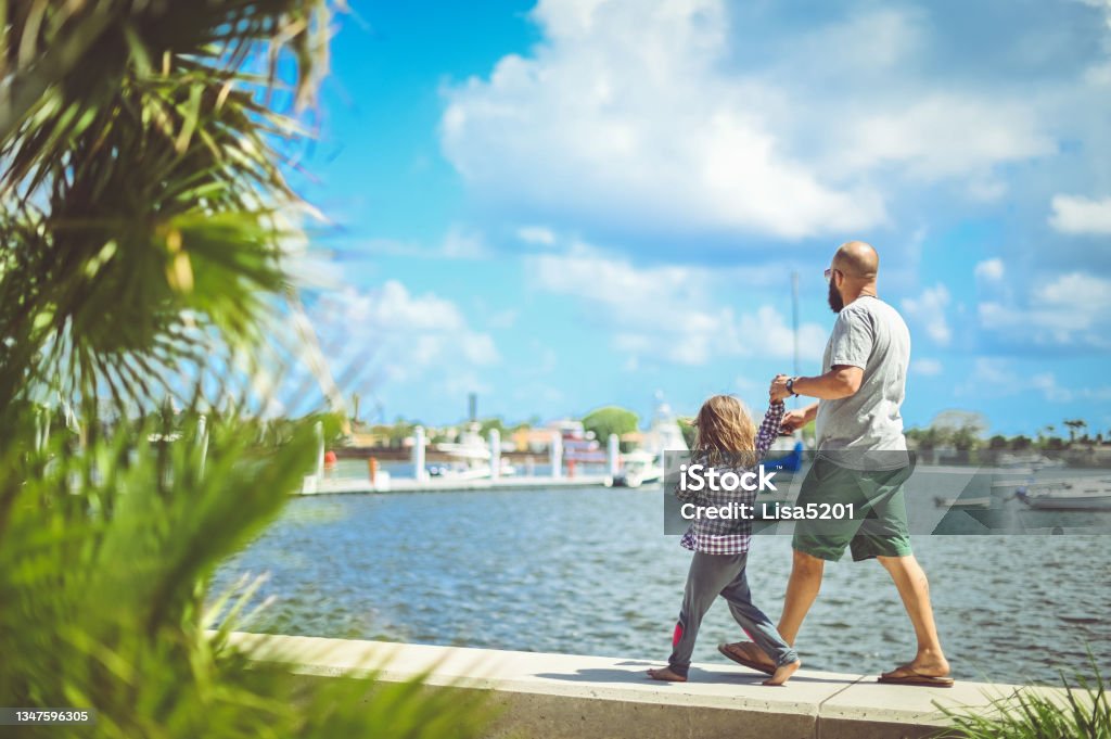 Father and daughter walk along the waterfront in sunny tropical location Sunny Florida family vacation Family Stock Photo