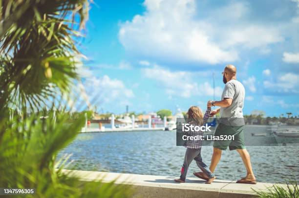 Father And Daughter Walk Along The Waterfront In Sunny Tropical Location Stock Photo - Download Image Now
