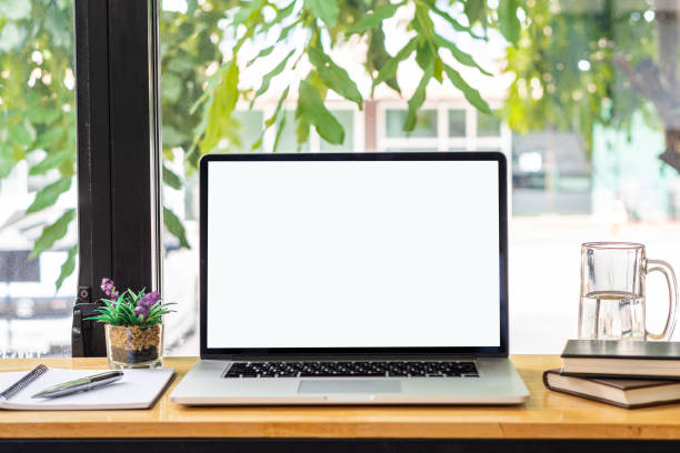 istock blank white screen laptop and computer screen Flower vases of plants and book objects on the table in a coffee shop front view beside the mirror 1347598284