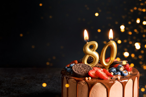 A chocolate birthday cake with candles and the number 60 on it.