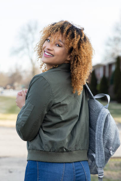 istock Woman wearing backpack and walking on sidewalk 1347599458