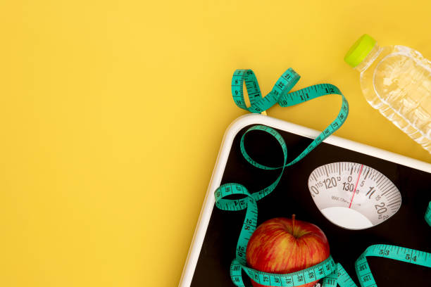 báscula de peso y cinta métrica con una manzana fresca, dieta saludable para el concepto de control de pérdida de peso - weight scale apple comparison balance fotografías e imágenes de stock