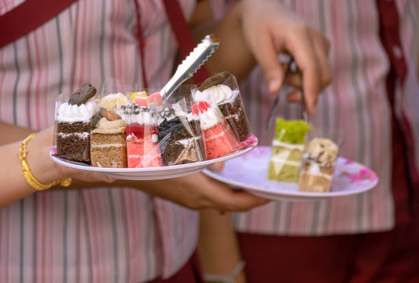 istock woman's hand holding plate of various mini cakes while choosing for takeout at bakery store 1347607796