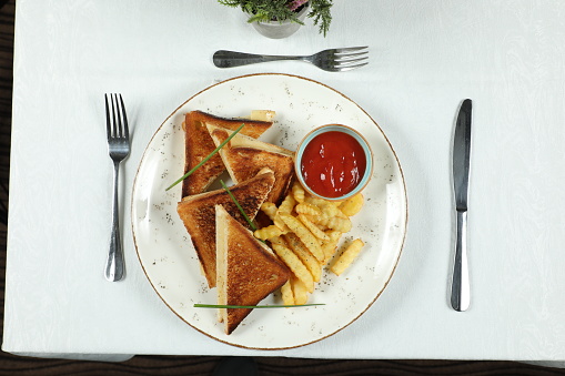 Club sandwich with french fries on plate in restaurant