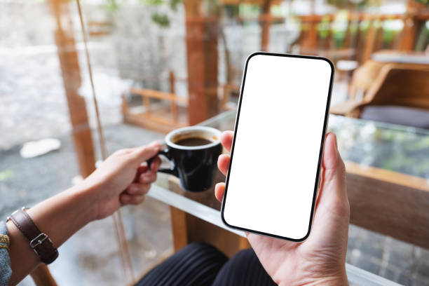 istock Mockup image of hands holding mobile phone with blank desktop screen while drinking coffee 1347615747