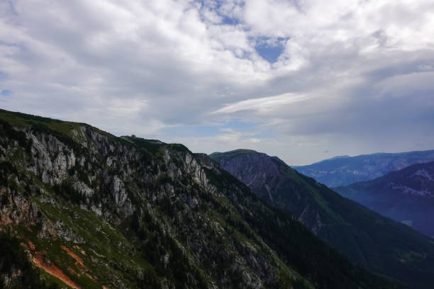 istock single alpine hut on the top from a huge rocky mountain with clouds 1347616332