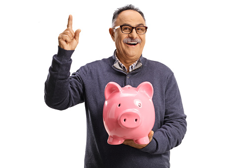 Mature man holding a piggy bank and pointing up