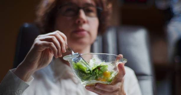 istock Mature woman is eating fresh vegetable salad at work 1347618194