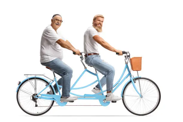Photo of Young and mature man riding a tandem bicycle