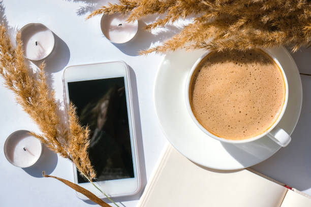 istock Pampas grass and white cup with coffee. Mobile phone with black screen. Checking social media Drinking Cappuccino in the breakfast morning at home. Flat lay. Wallpaper. Aesthetics 1347619274
