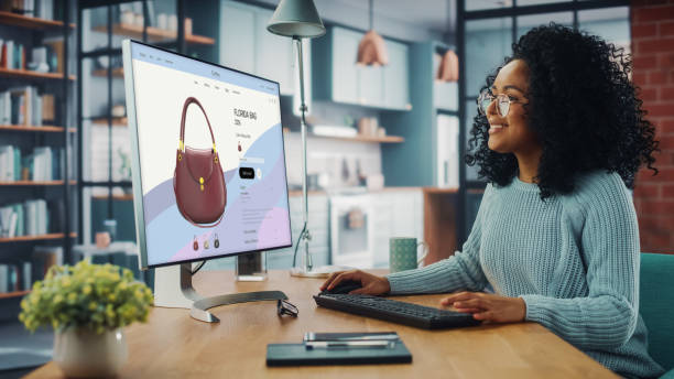 latina femme utilisant un ordinateur de bureau avec des vêtements boutique en ligne pour choisir et acheter des vêtements de la nouvelle collection. femme naviguant sur internet à la maison salon tout en étant assis à une table - achats en ligne photos et images de collection