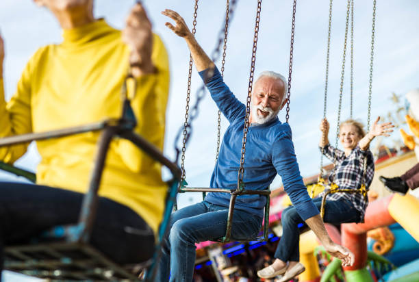 istock Happy seniors having fun during chain swing ride at amusement park. 1347626967