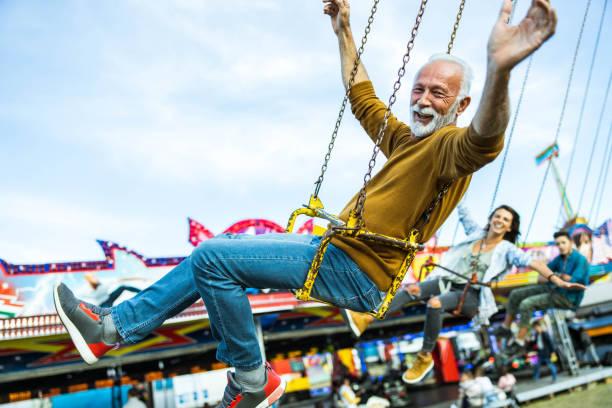 istock Happy senior man having fun while riding on chain swing at amusement park. 1347627052