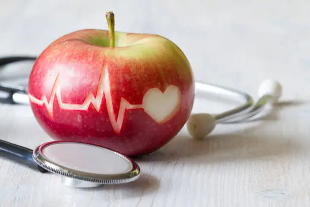 Photo of Heartbeat line on red apple and stethoscope, healthy heart diet concept