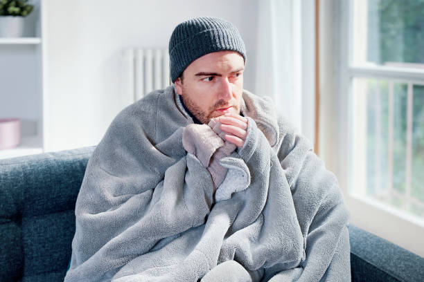 自宅暖房のトラブルで自宅で寒さを感じる男 - 溶解 ストックフォトと画像